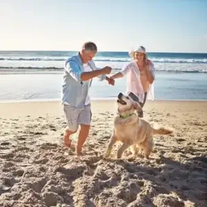 Couple playing with dog on the beach